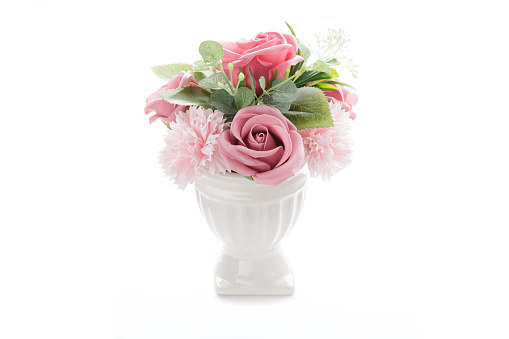Artificial flowers in a vase on a white background