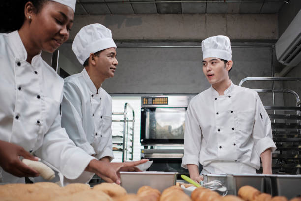 istock Chefs team in uniforms prepare to bake bread and pastry in stainless kitchen. 1399999656