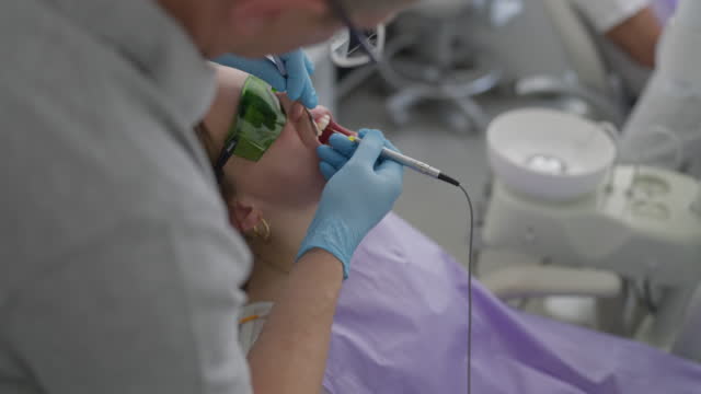 Caucasian male dentist descaling female patient dental plaque