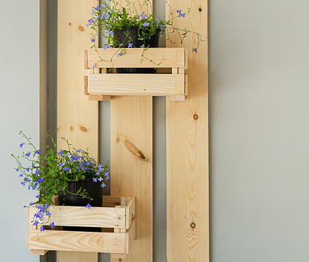 Decorative wooden wall with wooden boxes and potted flowers.