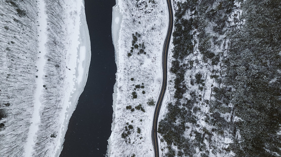 Aerial over a snowy road running alongside a river