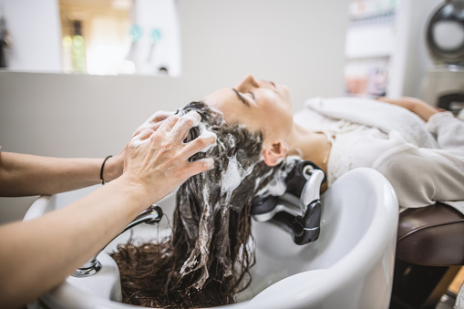 Beautiful woman getting a hair wash in a hair salon by hairdresser.