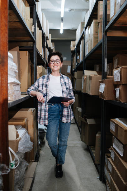 une employée de la distribution d’entrepôt exubérante tenant un presse-papiers - giving file document stack photos et images de collection