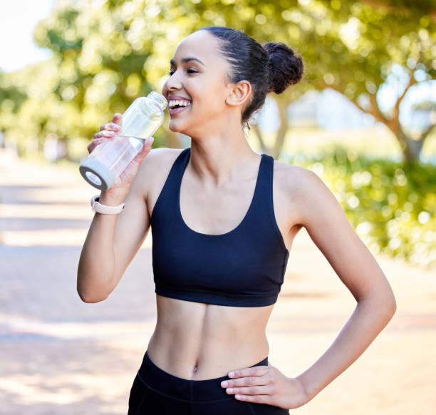 istock One fit young mixed race woman taking a rest break to drink water from bottle while exercising outdoors. Happy female athlete quenching thirst and cooling down after running and training workout 1400013338