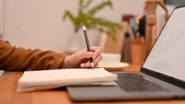 istock Female college student writing something on her school notebook and using laptop 1400020977