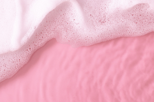 Top view of pink water surface with foam.Trendy abstract spring summer nature background for cosmetic product