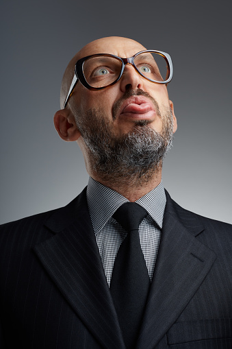 Studio portrait of a bearded businessman making faces and sticking out his tongue