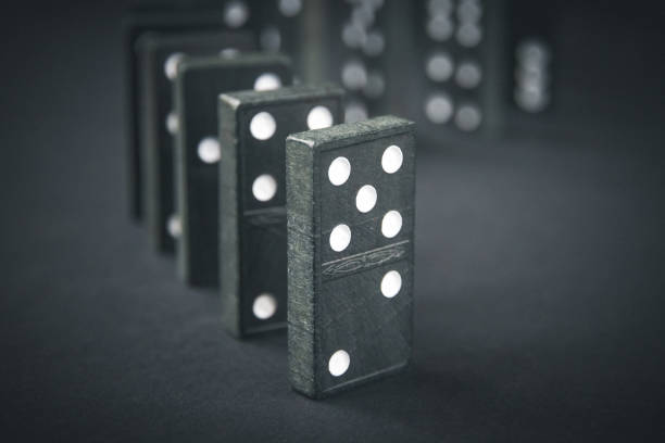 istock Black dominoes chain on dark table background 1400026314