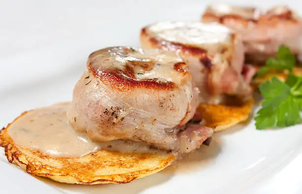 Pork medallions with potato pancake and herbs. Tasty nutritious meal