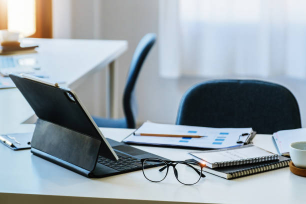 istock Focus on glasses with coffee mugs, books, documents with tablet computers on the desk 1400027674