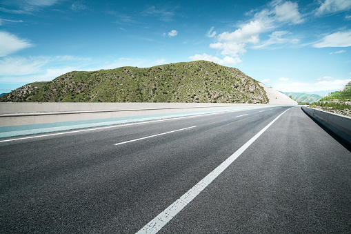 Empty parking area floor and concrete wall with mountain and blue sky lake view. 3D rendering background image for car scene.