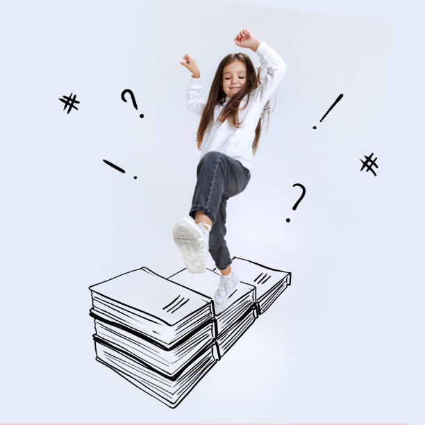 グレーの背景に隔離された絵の本を踏む学齢期の少女というコンセプチュアルなイメージ。子供時代、夢、想像力、教育、広告コンセプト。コラージュ - school supplies child back to school book ストックフォトと画像