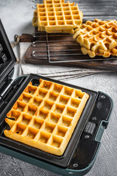 istock Cooking of fresh waffles in waffle maker. White background. Top view 1400039076