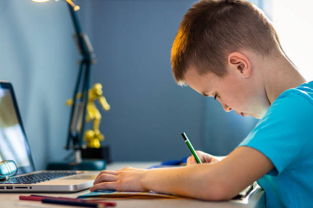 istock Boy sitting at the desk doing homework at home. 1400040944