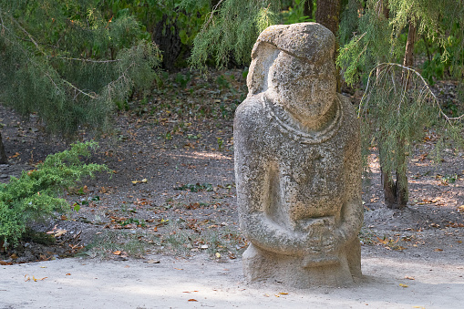 Stone ancient woman antiquated ruins statue in green park, botanical garden, Askania-Nova, Kherson region, Ukraine.