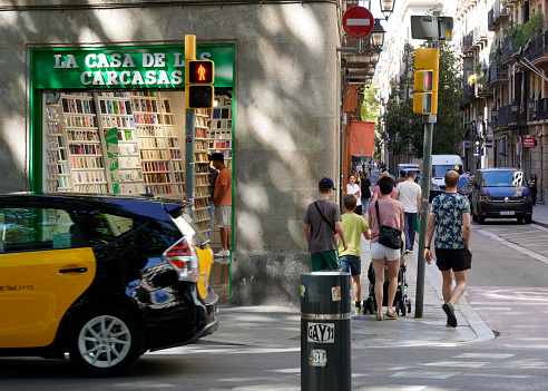 Barcelona, Spain - May 26, 2022: Large family walk together through a big city between heavy traffic and busy sidewalks