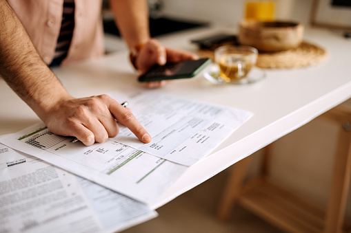 Unrecognisable man using calculator on the phone to calculate expenses