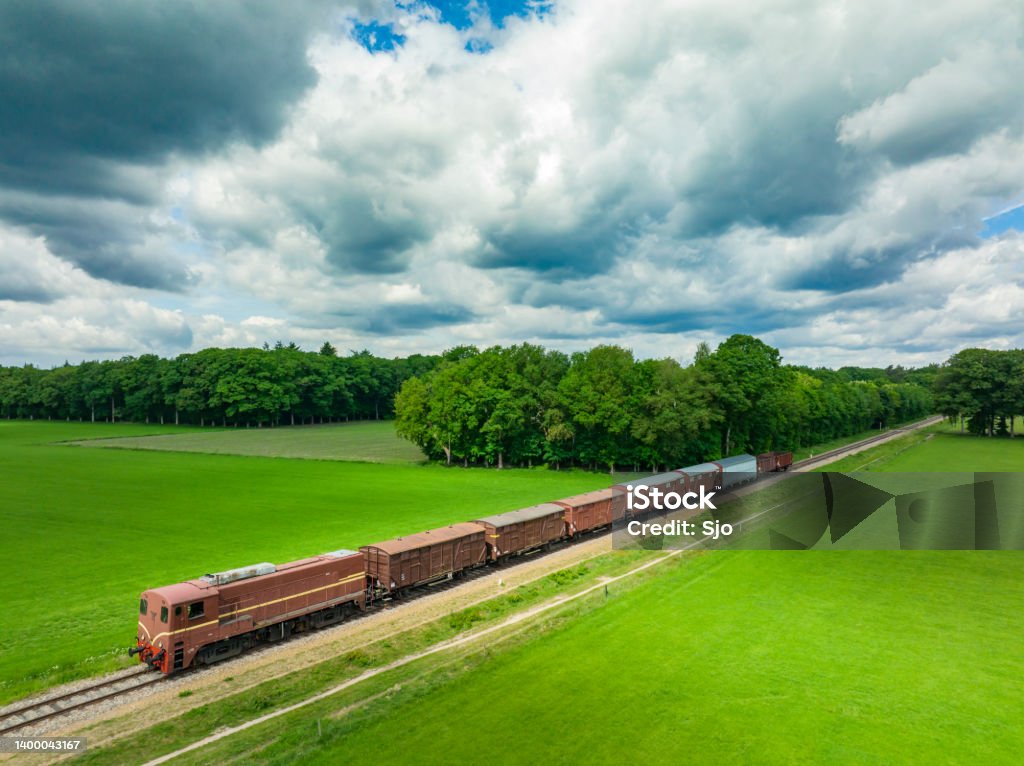 Old diesel freight train in the countryside Old diesel freight train in the countryside seen from above. The antique diesel locomotive is pulling freight cars over a railroad track through the woods and fields. Rail Freight Stock Photo
