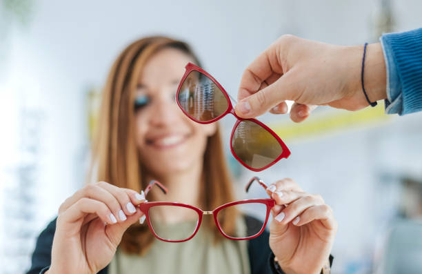 A young Latina in an optician's shop tries on glasses with a magnet accessory. stock photo