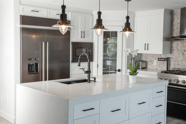 Black and white modern kitchen Black pendent lights over quartz counter top with over size stainless fridge in this newly renovated kitchen. kitchen stock pictures, royalty-free photos & images