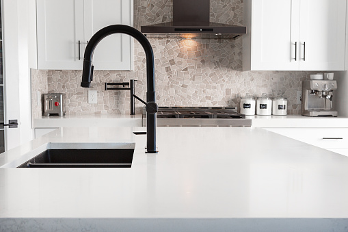 Black double granite rectangle sink with white over size quartz counter in newly renovated kitchen.