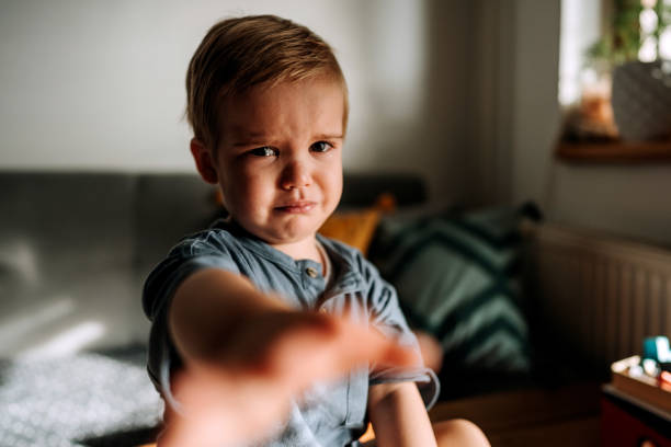 Cute little crying toddler reaching for camera stock photo