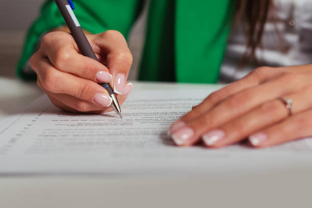 istock Businesswoman's hand with pen completing personal information on a form 1400043797