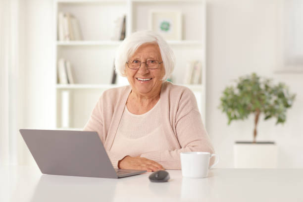 istock Happy elderly woman sitting at home with a laptop computer 1400047832