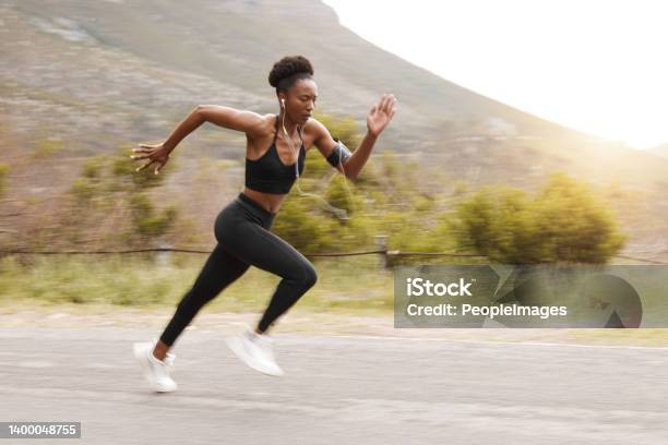 Motion Blur Full Body Fit Active African American Woman Running Fast While Exercising Outside In Nature Strong Athletic Black Woman Sprinting During Workout While Listening To Music With Earphones Stock Photo - Download Image Now