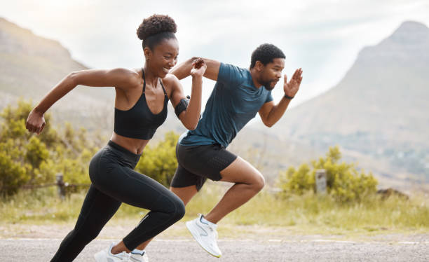 en forme, un couple afro-américain court à l’extérieur tout en faisant de l’exercice. jeunes hommes et femmes athlétiques s’entraînant pour améliorer leur cardio et leur endurance pour un mode de vie sain. ils adorent s’entraîner ensemble - sprint course sur piste photos et images de collection