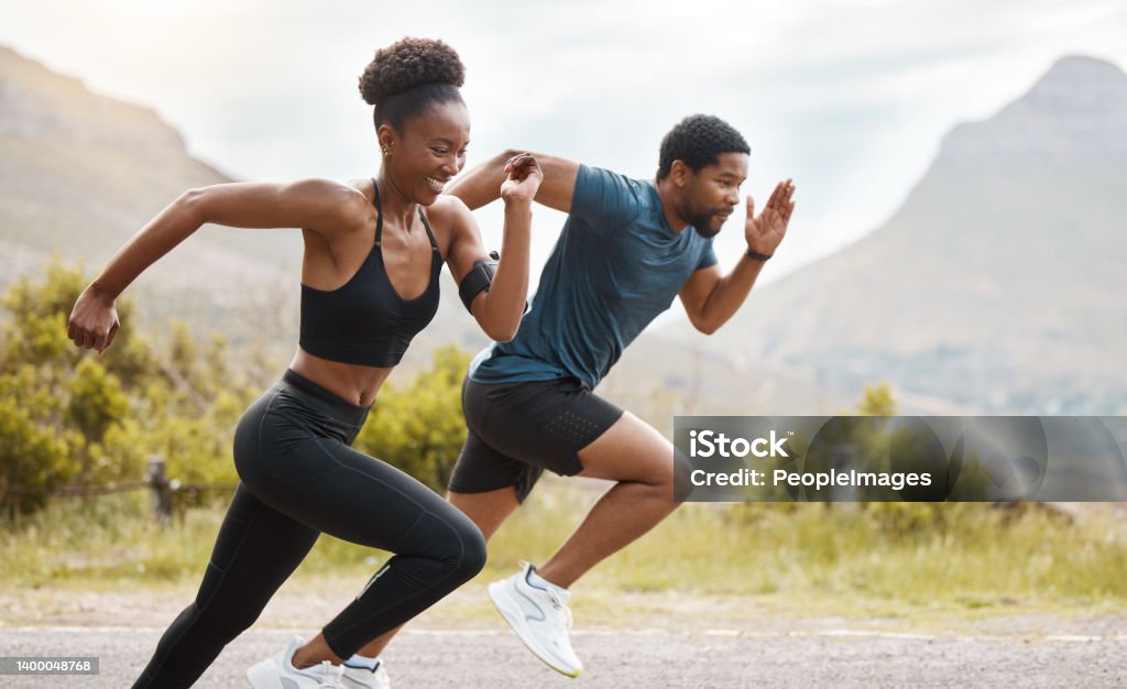 Fit african american couple running outdoors while exercising. Young athletic man and woman training to improve their cardio and endurance for a healthy lifestyle. They love to workout together Running Stock Photo