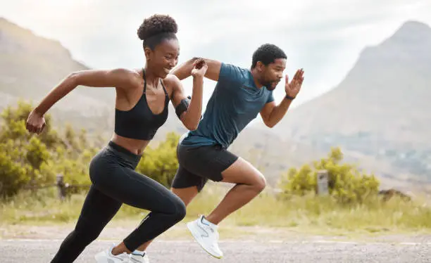 Fit african american couple running outdoors while exercising. Young athletic man and woman training to improve their cardio and endurance for a healthy lifestyle. They love to workout together