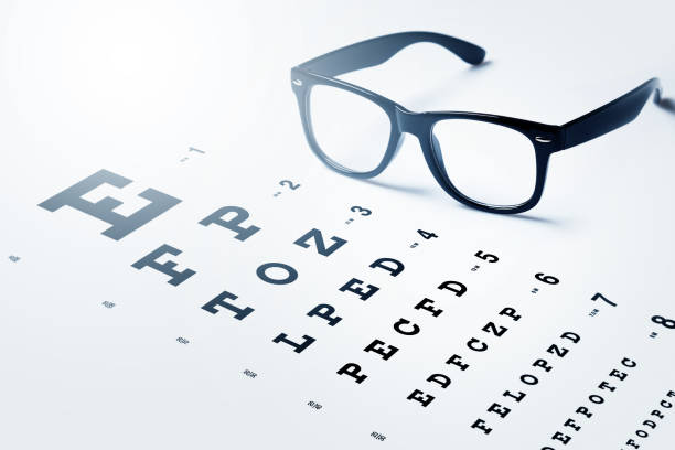 Eye chart for visual acuity testing and black rimmed eyeglasses stock photo