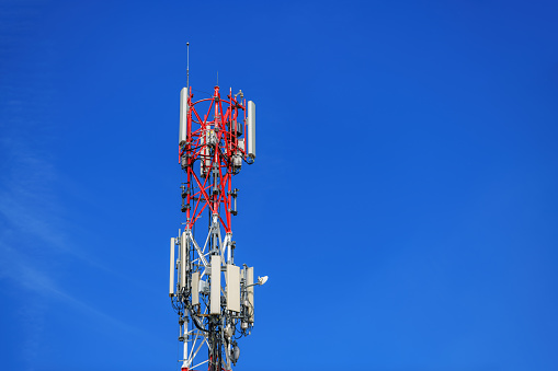 Telecommunication pylon with signal repeaters and antennas against blue sky for wireless technology and broadcasting industry concept, copy space included