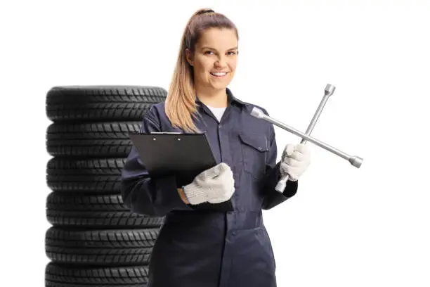 Young female mechanic worker holding a plug wrench and a clipboard isolated on white background