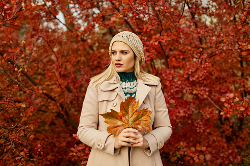 Young woman holding autumn leaf in hands