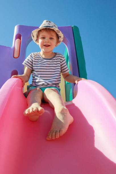 istock Happy child playing with pink slide on blue sky background. Playtime concept. 1400054555