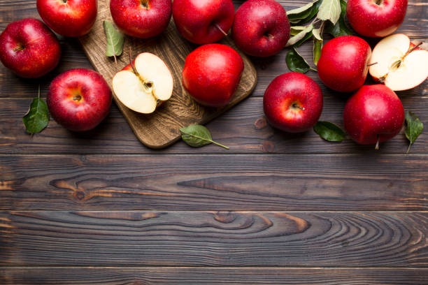 istock Fresh red apples with green leaves on table. cutting board with knife. Top view 1400054831