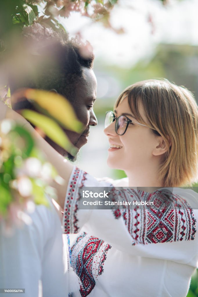 Portrait Of Interracial Couple Embracing In Spring Garden Dressed In 