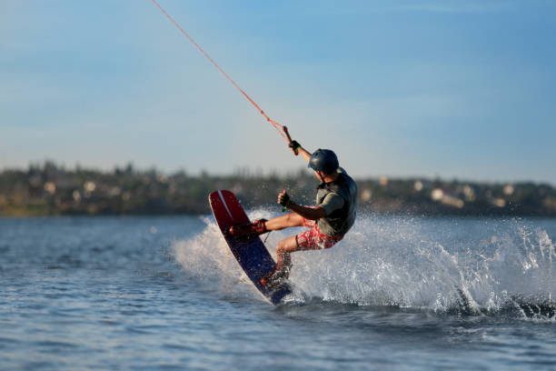 teenager wakeboarding auf dem fluss. extremer wassersport - wakeboarding stock-fotos und bilder