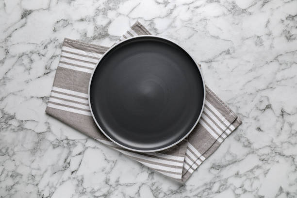 istock New dark plate and napkin on white marble table, top view 1400056762