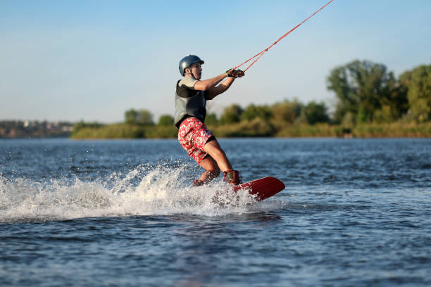 ragazzo adolescente wakeboard sul fiume. sport acquatici estremi - wakeboarding surfing men vacations foto e immagini stock