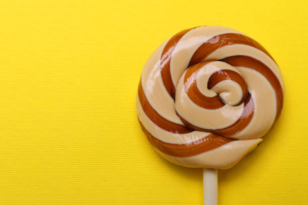 Delicious lollipop on yellow background, top view. Space for text
