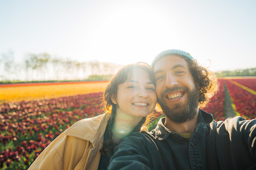 Selfie of young Caucasian heterosexual couple on tulip field in the Netherlands