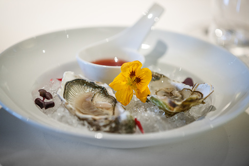 Fresh oysters served in plate with plenty of ice and a dipping bowl of savory sauce
