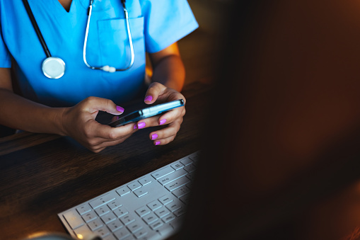 Closeup shot of an unrecognizable nurse using a cellphone in a hospital