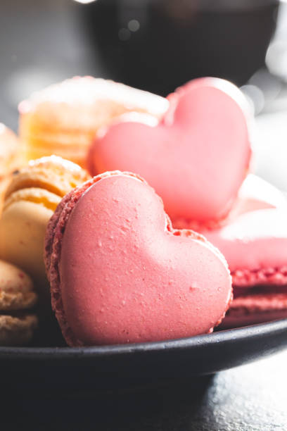 istock Heart shaped Sweet macarons on black table. 1400060417