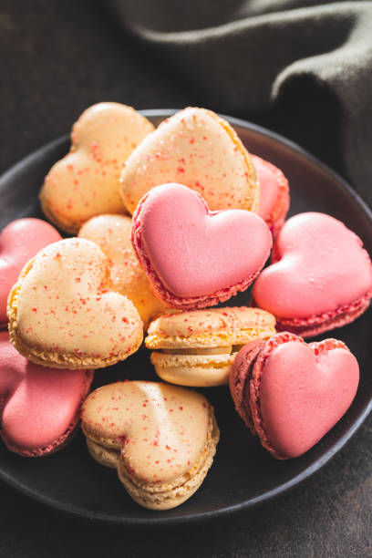 istock Heart shaped Sweet macarons on black table. 1400060418