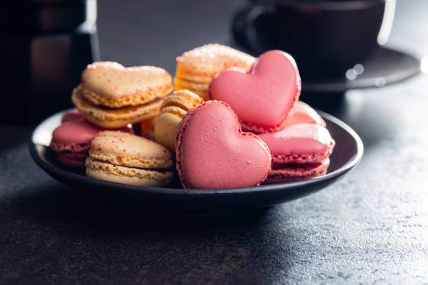 Heart shaped Sweet macarons on black table.