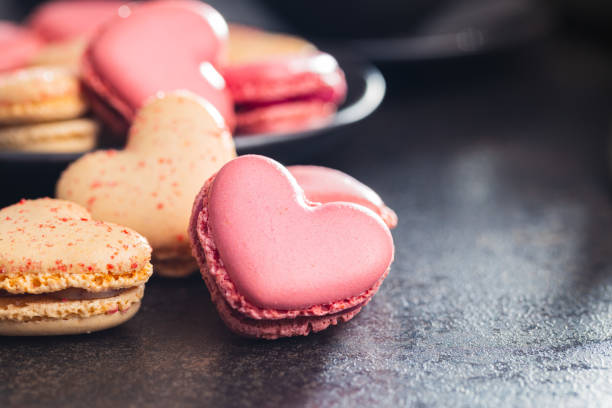 istock Heart shaped Sweet macarons on black table. 1400060496